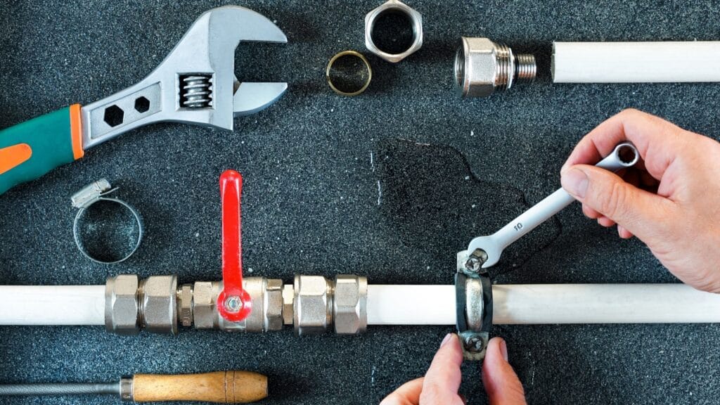 Plumber repairing a pipe valve with an adjustable wrench in Lebanon