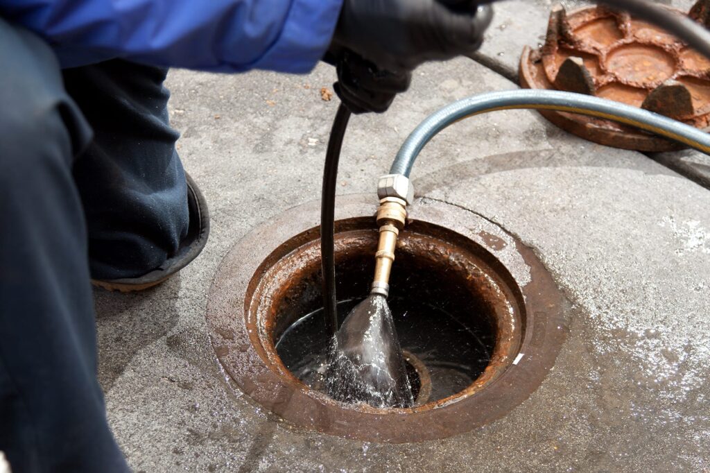 Plumber hydro jetting a sewer line through a manhole in Lebanon