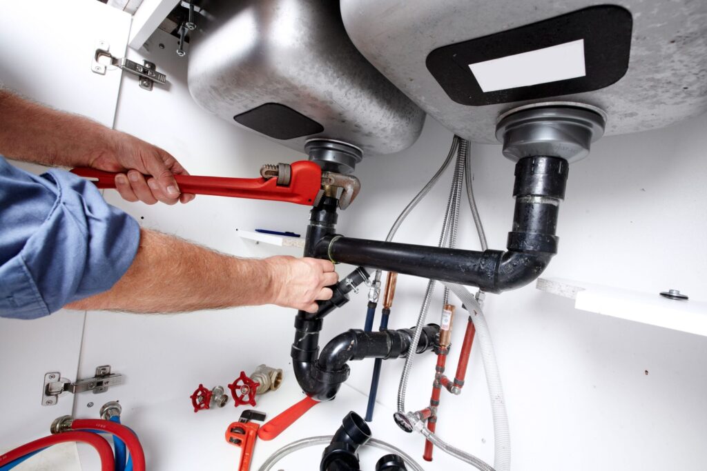 Plumber repairing drain pipes beneath a kitchen sink in Lebanon