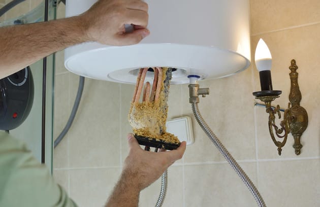 Technician removing mineral buildup from a water heater in Lebanon
