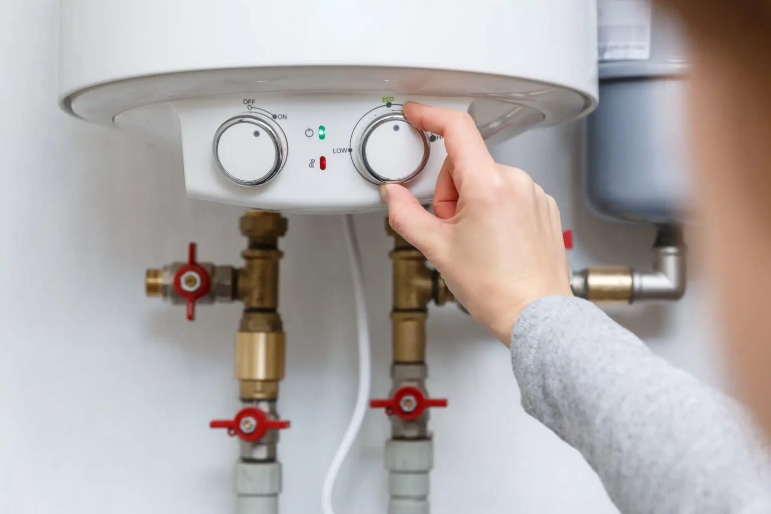 Homeowner adjusting the temperature controls on a water heater in Lebanon